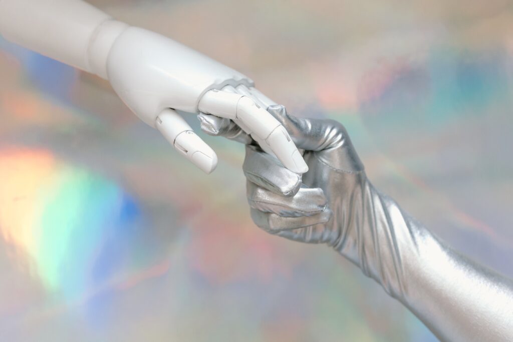 pexels-photo-8849283-8849283 Close-up of a robot hand and silver-gloved hand touching, symbolizing human-robot connection.